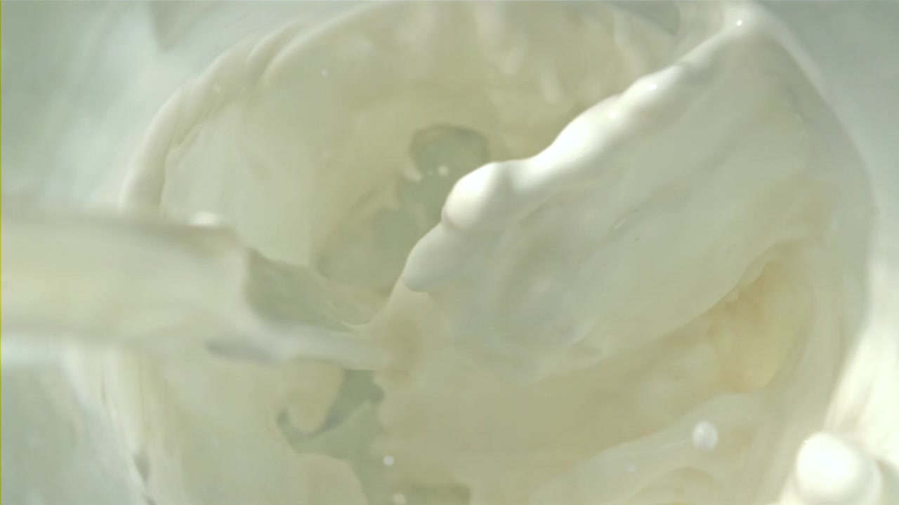 スローモーション：グラスに牛乳を注ぎ、しぶきと泡が立つ様子。