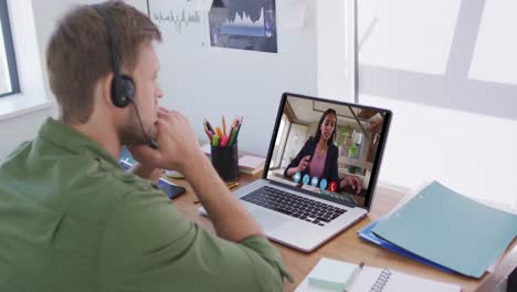 Caucasian-man-using-laptop-and-phone-headset-on-video-call-with-female-colleague