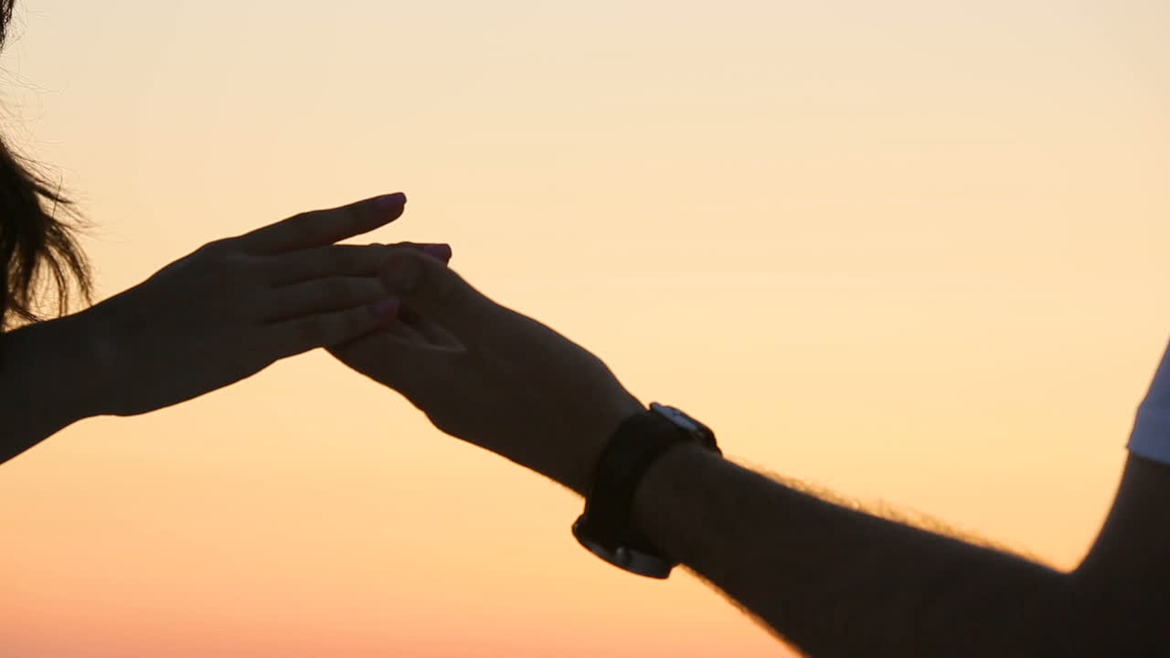 Man putting ring on woman hand. Close up of silhouette man putting ring on woman hand at sunset