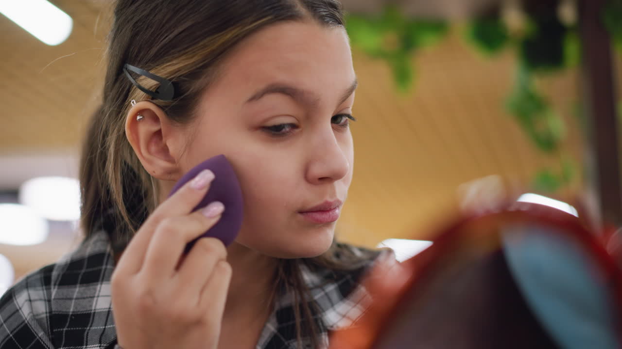joven artista ajustando cuidadosamente el maquillaje al lado de los ojos usando esponja de belleza para un acabado impecable, expresión enfocada destaca la precisión, la rutina de belleza y la atención a los detalles en el cuidado personal
