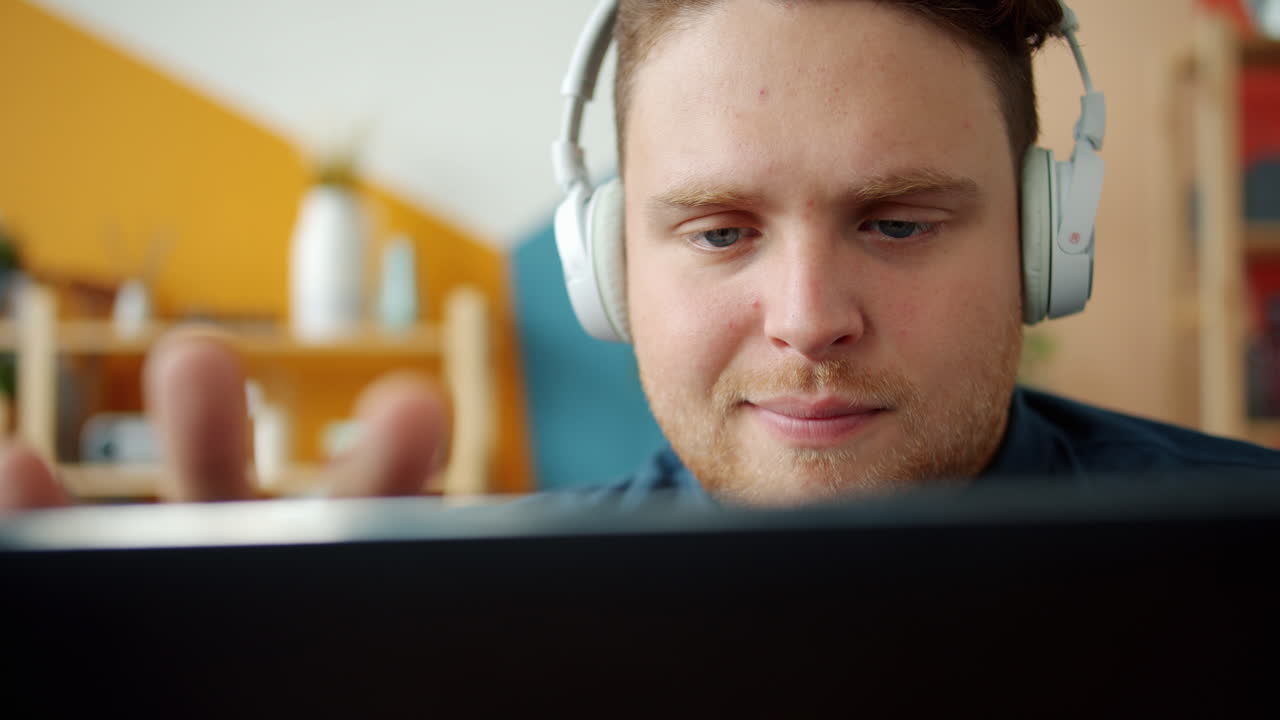 hombre trabajando en una computadora portátil con auriculares