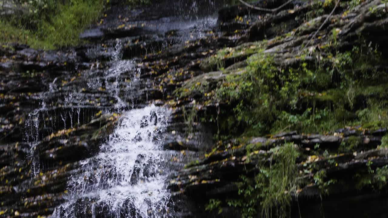 Tilting shot showing the full rocky waterfall coming from the river Gorge