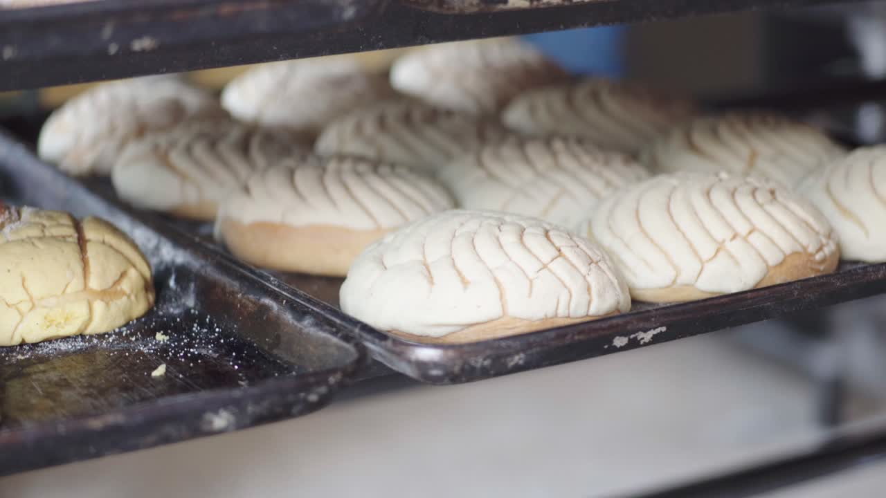 Close-up of multiple trays filled with assorted baked pastries cooling on racks inside a bakery.