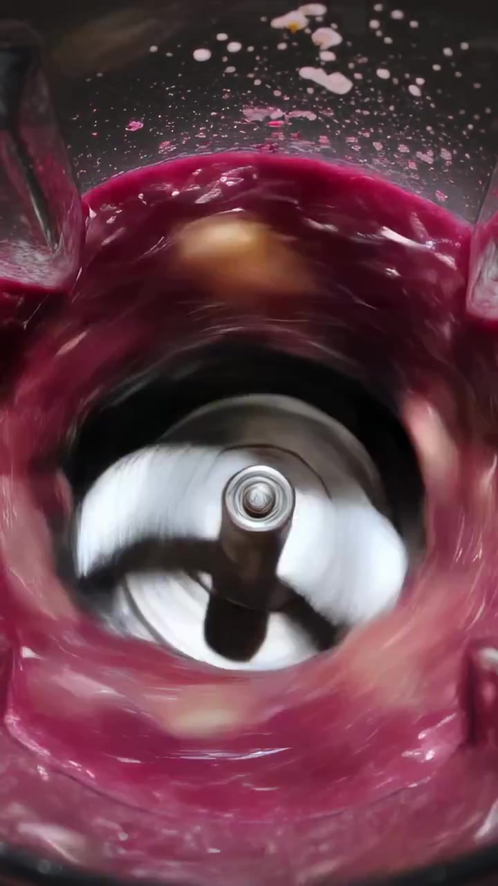 Vertical video: Pouring water, blade spinning in jar on counter, making pink smoothie with banana