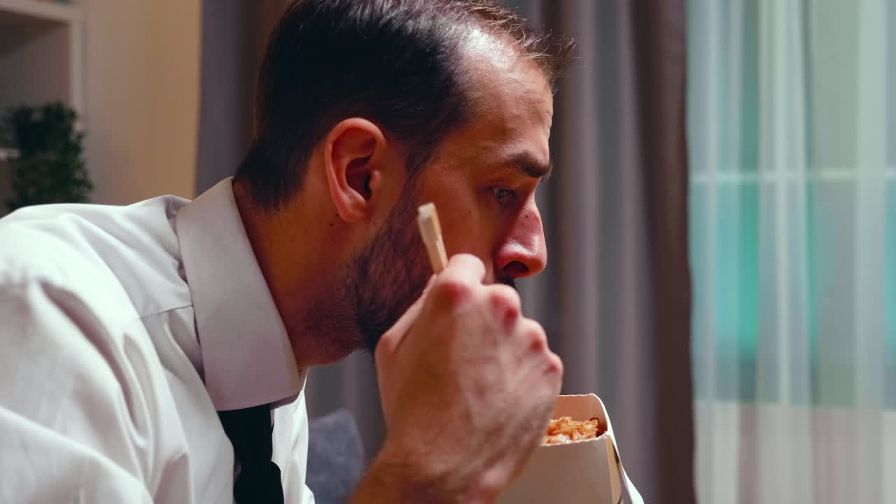 Close up of businessman with tie eating noodles from a box