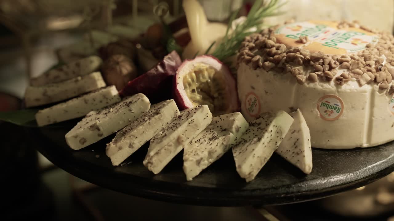close up of creamy cheese slices with herbs and passion fruit on rustic platter at catering event