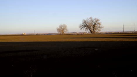 long shadows stretching over arid farm land field during sunset, time lapse