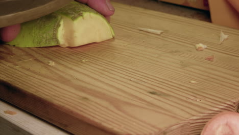 low angle macro view: knife cuts rutabaga vegetable on wooden board