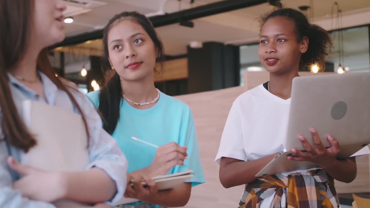 A group of friends discussing homework in a coffee shop. Multiethnic students having fun chatting in school.