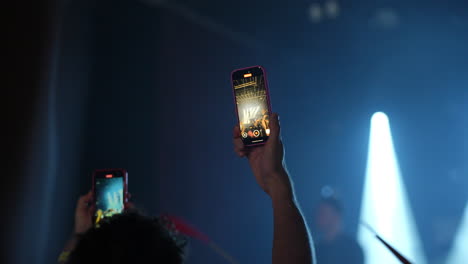 audience capturing live performance with smartphones under vibrant stage lights and atmosphere