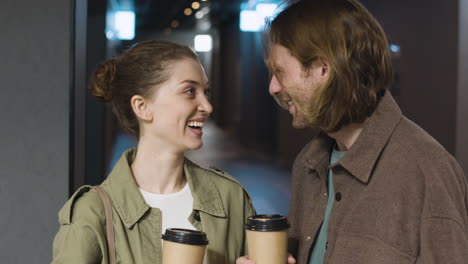 happy couple holding takeaway drinks, talking together and walking to the movie theater