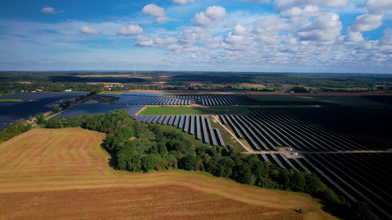 снимок с воздуха огромной солнечной электростанции на фоне красочных сельских полей летом