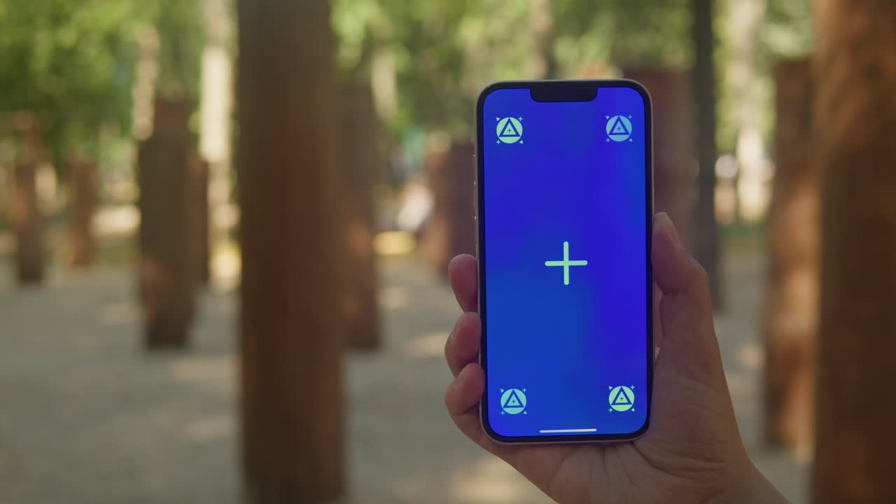 Young woman holding phone chroma key screen in front of playground close-up. Girl with green screen on smart phone. Nature