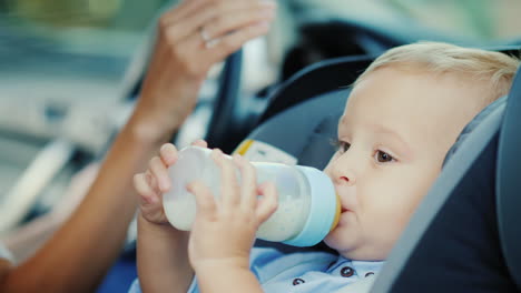Baby-1-Jahr-Alt-Trinkt-Milch-Aus-Einer-Flasche-Sitzt-In-Einem-Kinderautositz-4k-Video
