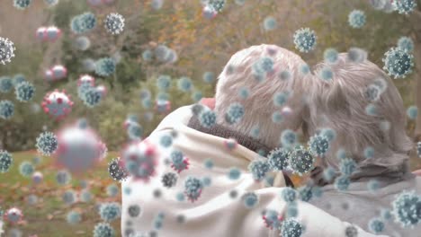 animation of covid 19 cells over senior couple embracing