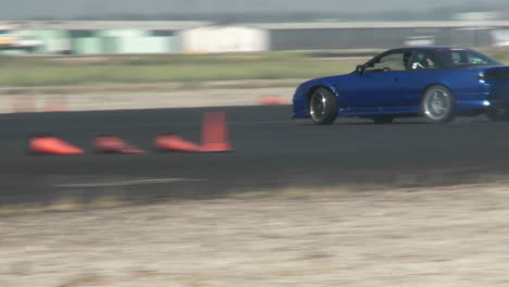 a blue car squeals its tires as it is skillfully guided through a drifting course in at camarillo airport in camarillo california