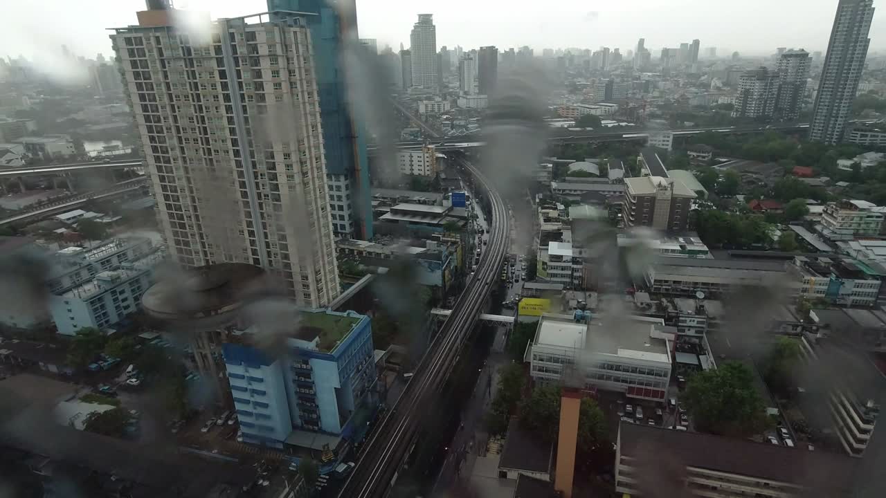 la lluvia cae por la ventana. vista aérea. la lluvia fuera de la ventana de la sala de estar en la temporada de lluvias en bangkok, tailandia. la ventana exterior está borrosa por la lluvia del edificio de la ciudad y la carretera y el cielo.