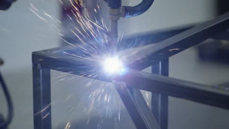 precision welding process captured: robotic arm applying high-temperature welding technique on metal frame with sparks flying
