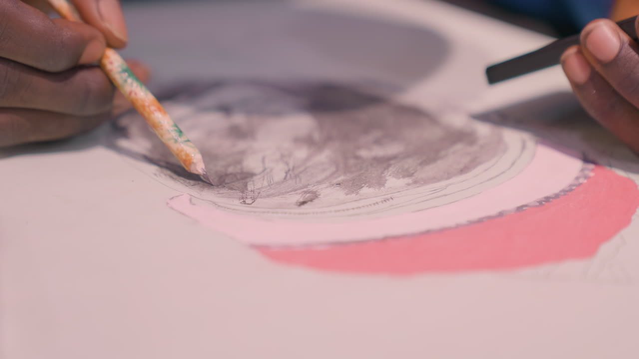 Closeup hands creating black painting wash with pink accent, black artist uses graphite and watercolor on paper, slow meditative strokes, textured smudge and fine detail, studio light highlights