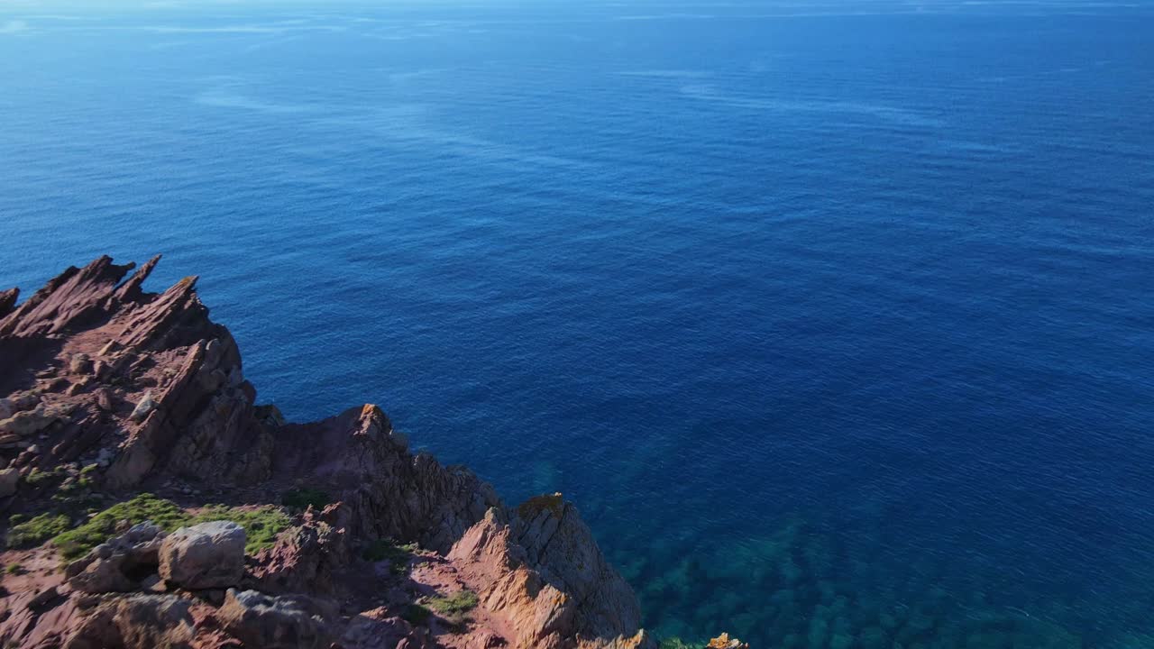 Drone flying over cliffs with reveal of shallow reef on the oceans edge of Menorca