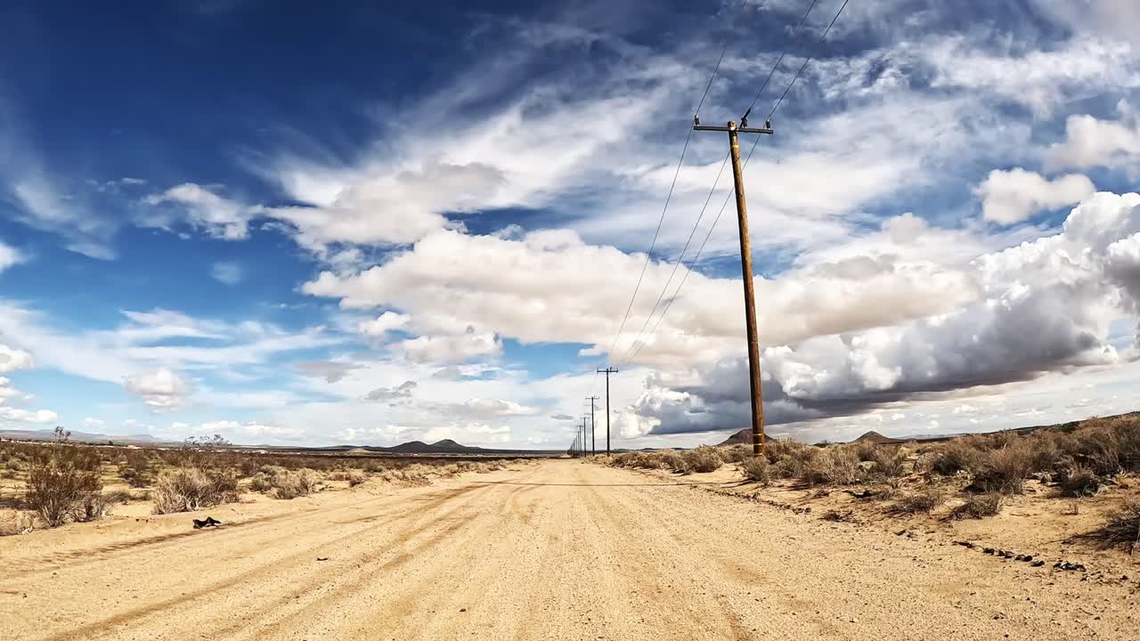 conduciendo por un solitario camino de tierra en el desierto de mojave - punto de vista del conductor
