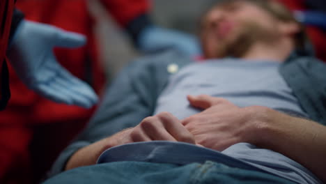 paciente acostado en camillas en el coche de ambulancia. hombre cansado con dolor en el estómago