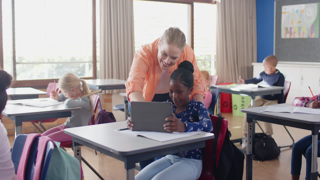 A scuola, una maestra aiuta uno studente con un tablet in classe, altri studenti studiano.