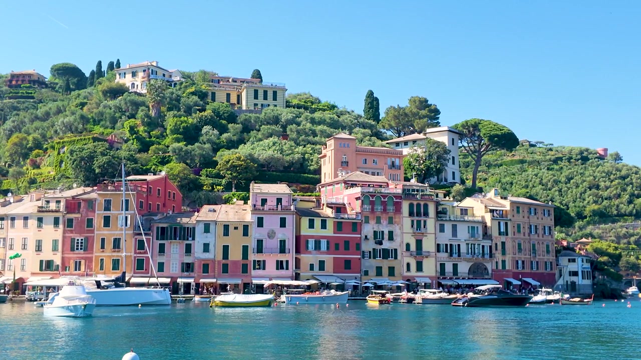 Ampia inquadratura statica di vivaci edifici costieri e barche di lusso sotto un cielo azzurro e limpido.