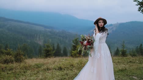 Beautiful woman in wedding dress with bouquet outdoors. Full-length portrait of a young bride on the mountains background.
