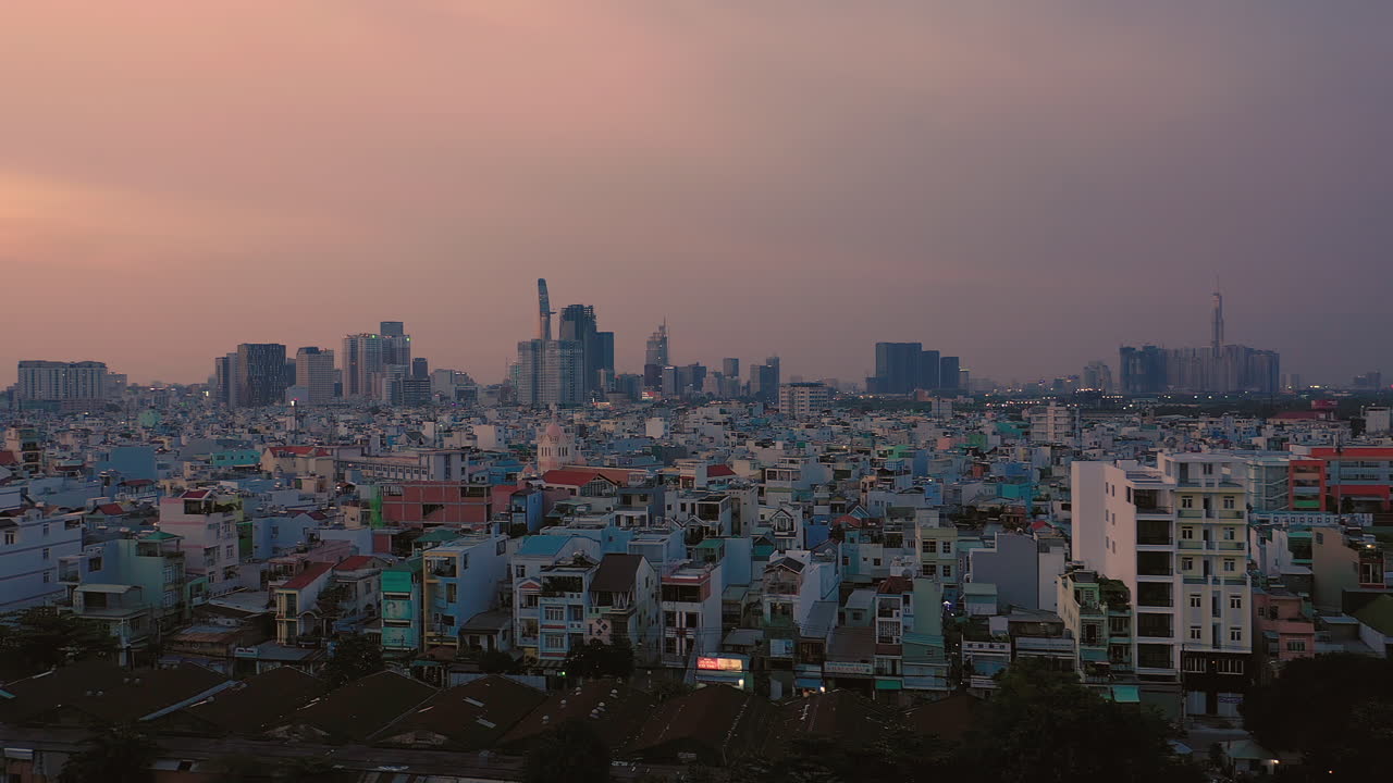 저녁 드론 샷은 오른쪽에서 왼쪽으로 이동하여 도시의 주거 지역을 배경으로 인식할 수 있는 큰 건물을 보여줍니다.