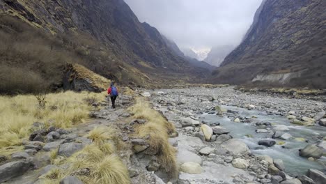 hombre caminando junto al río en un valle entre las montañas