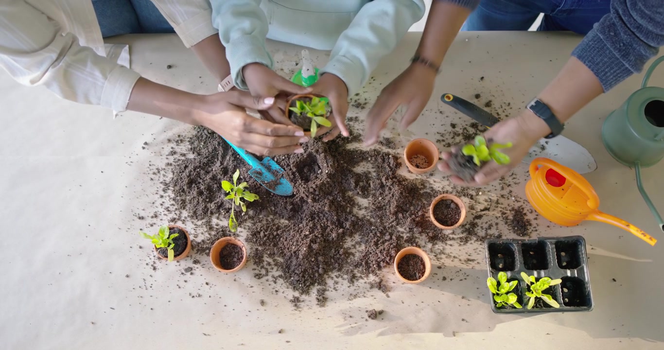 Family with youth planting seedlings at table after arranging tools, scooping soil, watering pots