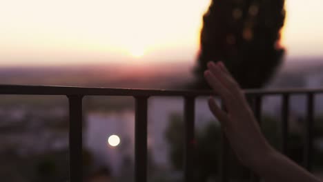 slow motion shot of a woman running her hand along a railing during sunset