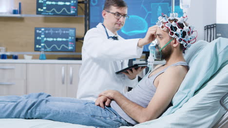 doctor holding tablet and making adjustments on brain sensors attrached to patient