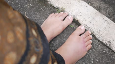 woman's bare feet with bruised toe on sidewalk