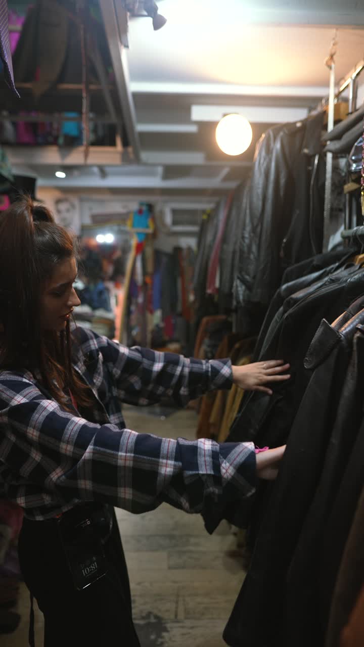 mujer comprando chaquetas de cuero vintage en una tienda de segunda mano