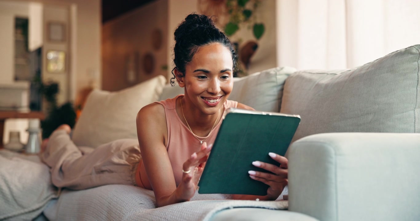 Young Woman Relaxing on Sofa Using Digital Tablet at Home