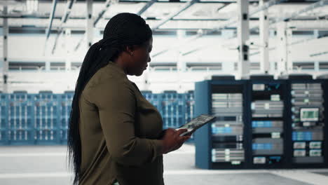 smiling engineer walking in data center with laptop, checking hardware