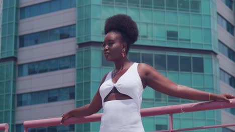 a black girl in a white dress on a rooftop with a city view