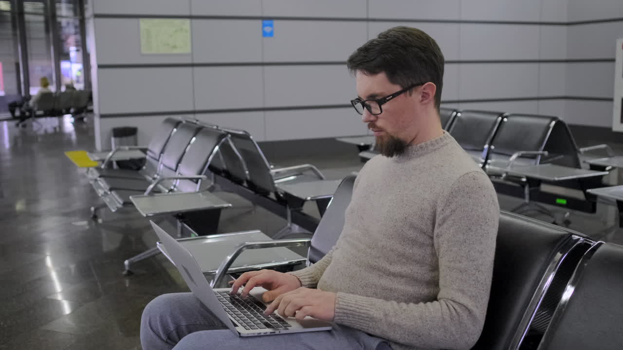 hombre trabajando en una computadora portátil en la zona de espera del aeropuerto
