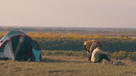 guy sits near boyfriend at campfire and supports sad man