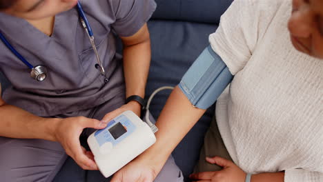 assisting senior woman, healthcare professional measuring blood pressure with monitor