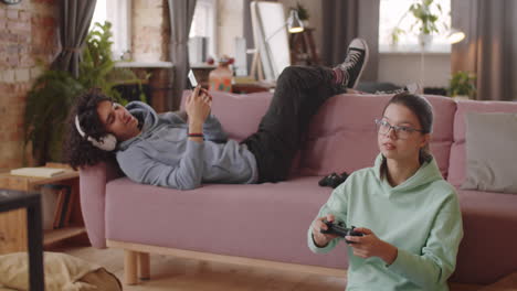 teen kids using smartphone and playing console game at home