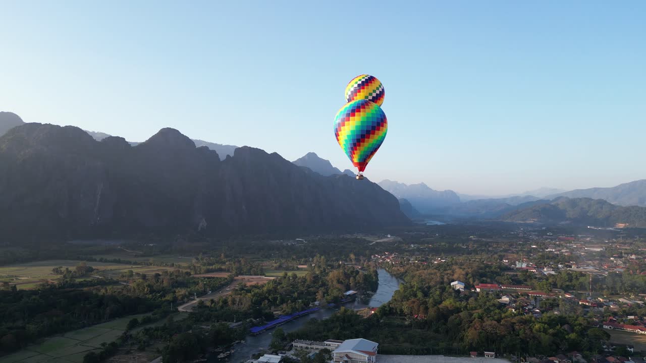 tomada de un avión no tripulado de coloridos globos de aire caliente flotando sobre el río en vang vieng, la capital de la aventura de laos