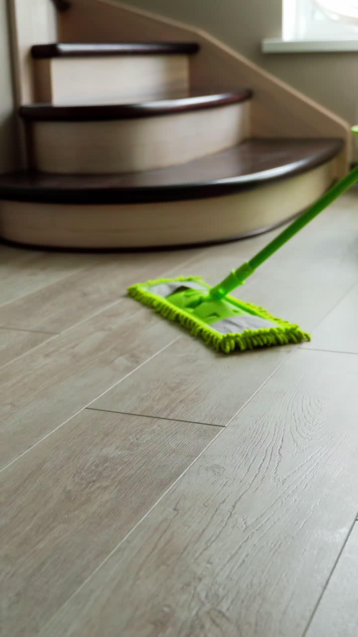 Washing the laminate floor with a mop. Housekeeper with mop and bucket is cleaning floor at home. Floor care concept. Vertical video