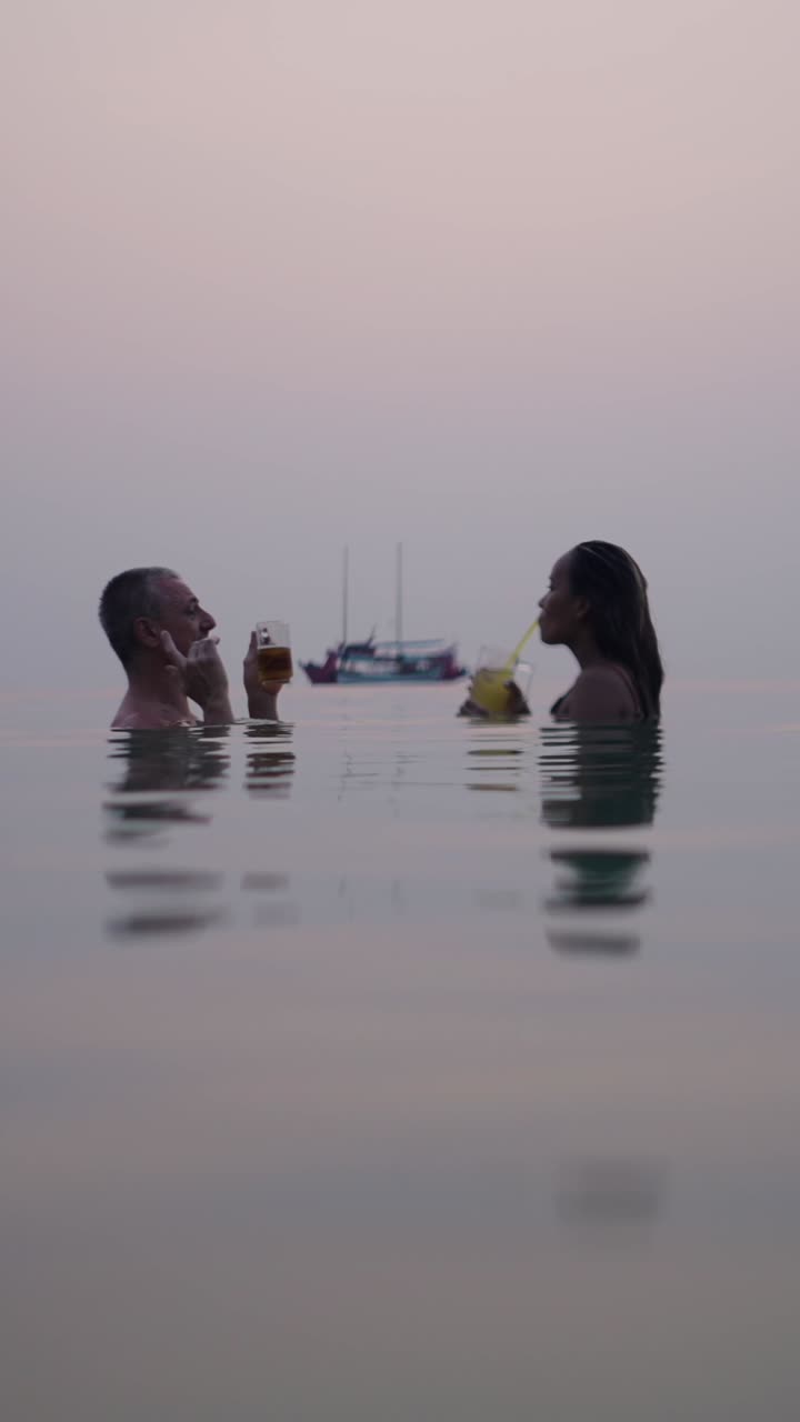 Couple Enjoying Drinks in an Infinity Pool at Sunset