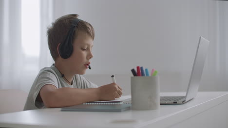 joyful boy is sitting on couch at home and talking cheerfully with someone by internet vacation time for schoolchildren online chatting