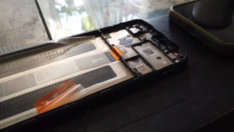 closeup hand held view of smartphone opened, microchip details of broken phone fixing process
