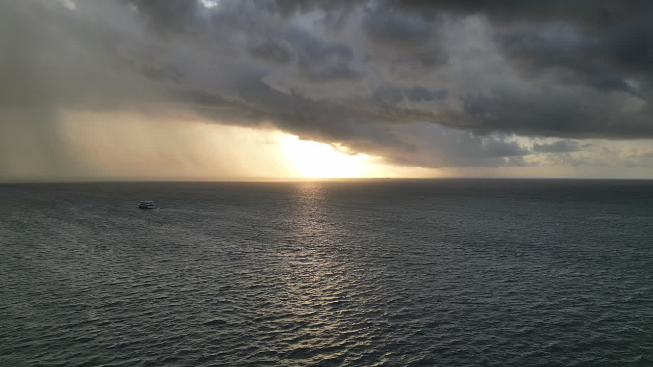 ferry navegando al atardecer en mar tranquilo con tormenta inminente en el horizonte, aérea