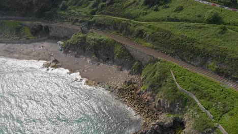 Top-down-view-of-busy-beach-on-a-bright-sunny-day-and-an-empty-railroad-by-the-sea